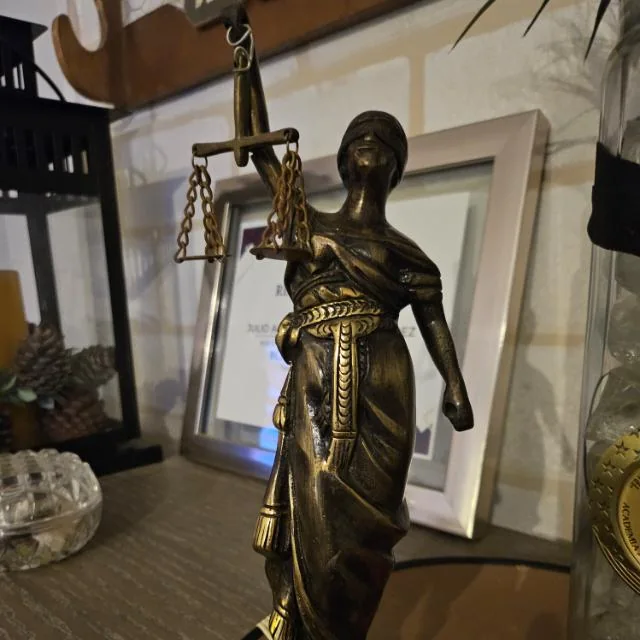 Figura decorativa de la justicia con espada y balanza, compartida como referencia del despacho